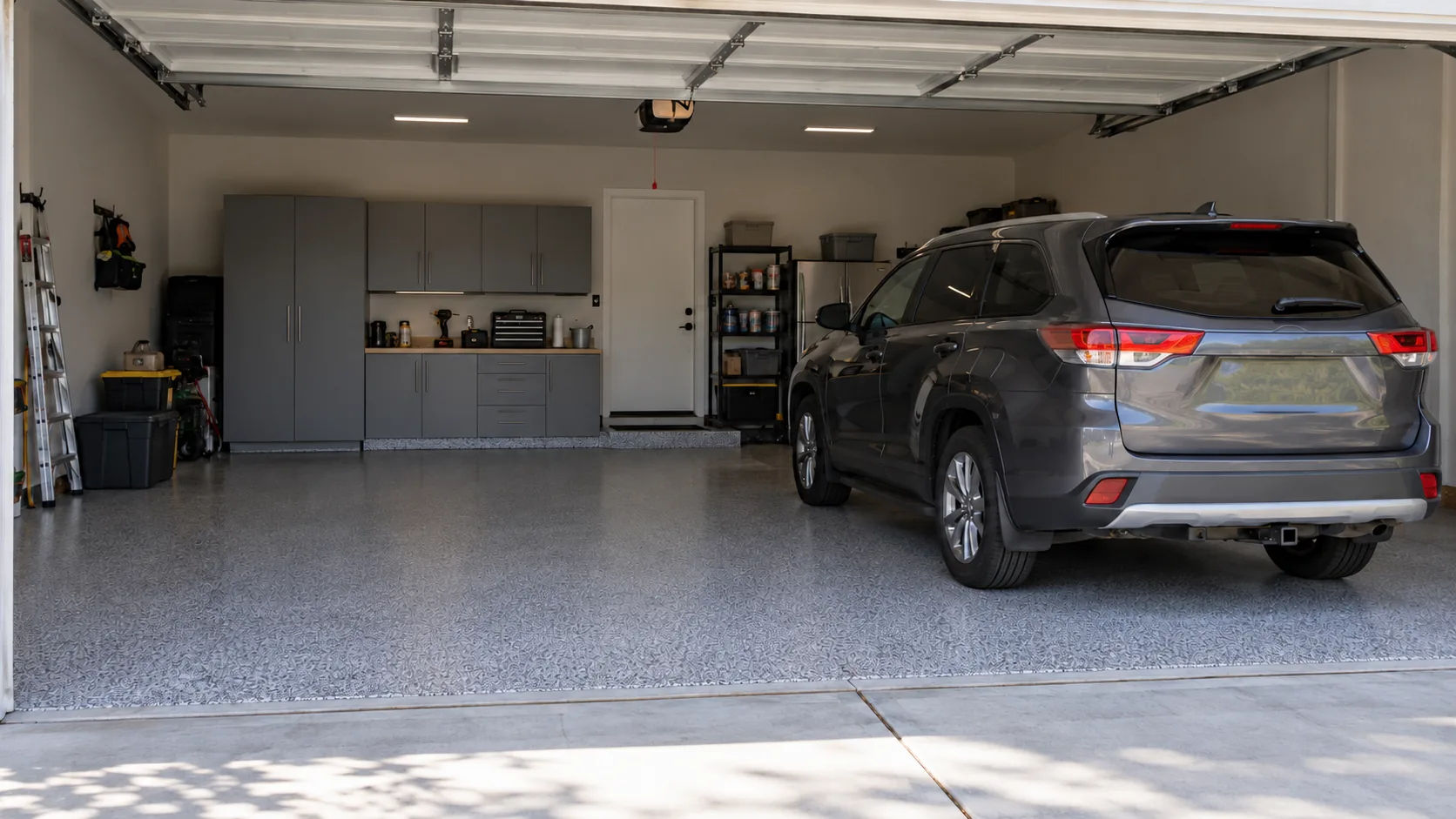 Garage with a glossy grey flake floor, black storage cabinets and a car parked inside